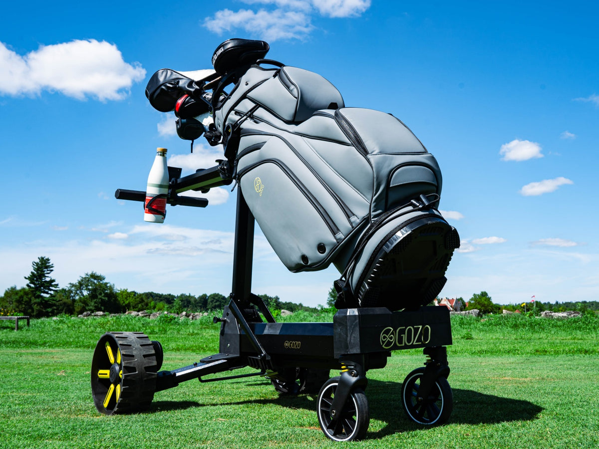 Gozo electric golf caddy carrying a gray golf bag on a sunny golf course under a blue sky